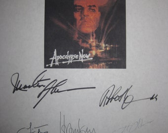 May include: A black and white poster with a movie still of a man's face. The poster is signed by Marlon Brando, Harrison Ford, Dennis Hopper, and others. The title of the movie is "Apocalypse Now".