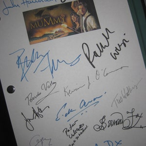 Puede incluir: Una hoja de papel blanca con varias firmas del reparto de la película "La Momia". Las firmas incluyen John Hannah, Oded Fehr, Brendan Fraser, Patricia Velasquez, Kevin J. O'Connor y The Watkins.