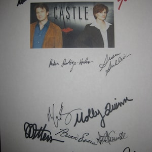 May include: A black and white photograph of the cast of the TV show "Castle" with their autographs. The cast includes Nathan Fillion, Stana Katic, Tamala Jones, Seamus Dever, Molly Quinn, and Jon Huertas.