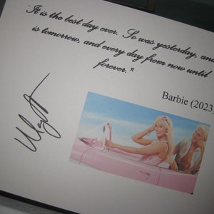 May include: A white card with a handwritten quote about the best day ever. The quote is signed "Barbie (2023)". A photo of a woman in a pink convertible is in the bottom right corner.