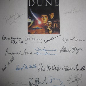 May include: A white sheet of paper with blue and black signatures from the cast and crew of the 1984 film "Dune". The signatures include Kyle MacLachlan, Patrick Stewart, Francesca Annis, and others.
