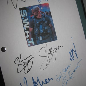 May include: A white sheet of paper with multiple blue and black signatures. The signatures include "Shemar", "L. James", "Geoff Pearce", "Paul  Gannas", and "S.W.A.T."  A photo of a man in a black uniform with the word "S.W.A.T." printed on it is in the upper right corner.
