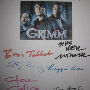 May include: A signed cast photo from the TV show "Grimm" featuring the main actors. The photo is signed by the actors Bitsie Tulloch, Silas Weir Mitchell, Reggie Lee, Claire Coffee, and Kate Burton.