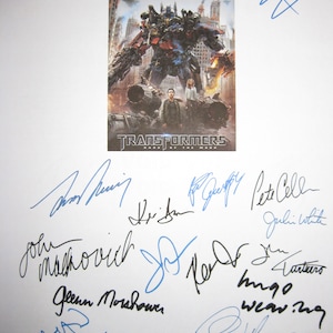 May include: A signed poster of the movie Transformers: Dark of the Moon. The poster features a large image of Optimus Prime, a robot character from the movie. The poster is signed by several actors and crew members, including Josh Duhamel, Tyrese Gibson, Peter Cullen, and Julie White.