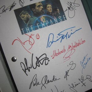 May include: A white sheet of paper with multiple signatures from the cast of the TV show "The Expanse". The signatures are in black, blue, and red ink. The show's title is written in black ink at the top of the page. A photo of the cast is in the upper right corner of the page.