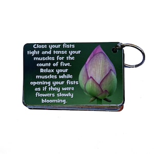 May include: A green and pink motivational keychain with a lotus flower image and the text "Close your fists tight and tense your muscles for the count of five. Relax your muscles while opening your fists as if they were flowers slowly blooming."