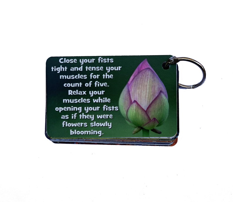 May include: A green and pink motivational keychain with a lotus flower image and the text "Close your fists tight and tense your muscles for the count of five. Relax your muscles while opening your fists as if they were flowers slowly blooming."
