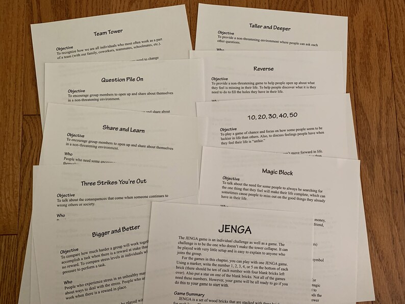 May include: A collection of white papers with black text outlining different team building games. The games include Team Tower, Question Pile On, Share and Learn, Three Strikes You're Out, Bigger and Better, Taller and Deeper, Reverse, 10, 20, 30, 40, 50, Magic Block, and Jenga.