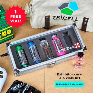 Peut inclure: Une mallette d'exposition argentée contenant cinq fioles de liquide coloré. L'intérieur de la mallette est noir. Une étiquette rouge en forme d'étoile dit "1 FREE VIAL!". Le texte "Exhibitor case & 5 vials KIT" est également visible.