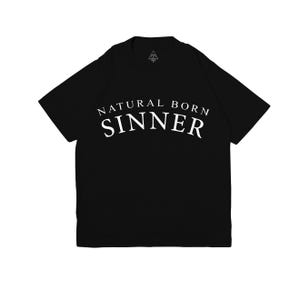 Könnte beinhalten: Schwarzes T-Shirt mit dem weißen Schriftzug "NATURAL BORN SINNER" in einem Bogen. Das Shirt hat einen Rundhalsausschnitt und kurze Ärmel. Ein kleines Logo ist in der Nähe des Halsausschnitts sichtbar.