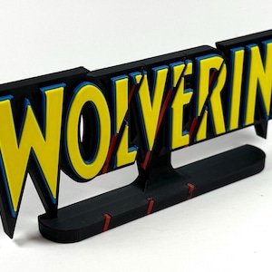 May include: A 3D printed sign with the word "WOLVERINE" in yellow letters with blue outlines and red slashes. The sign is mounted on a black base.