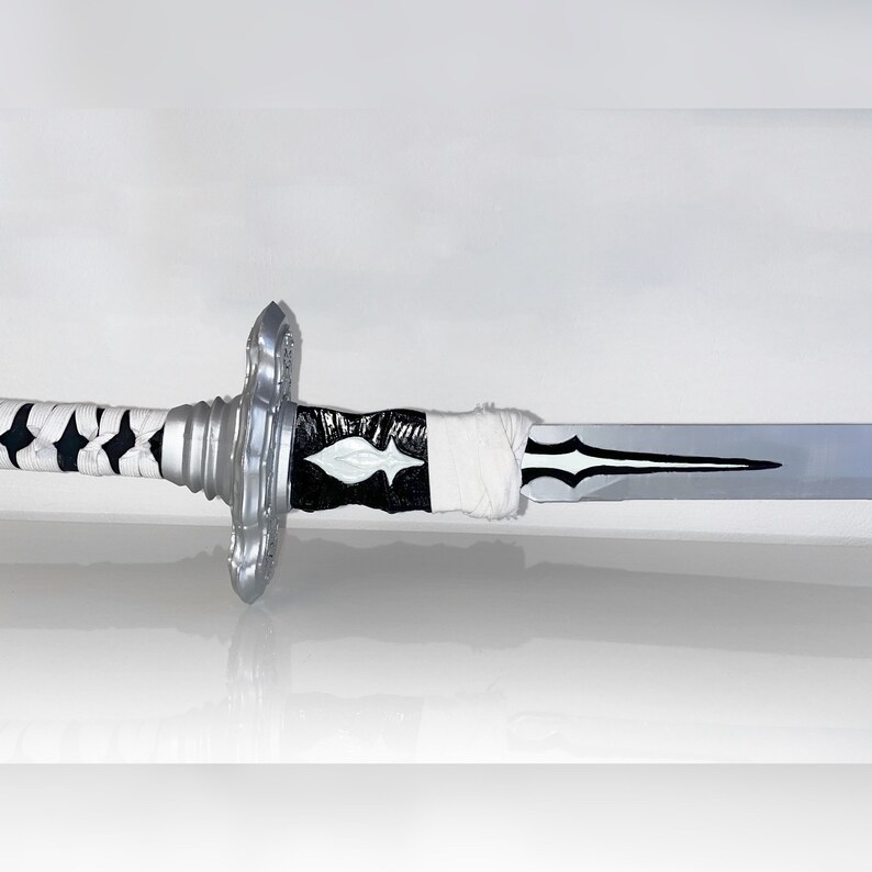 Pu&ograve; includere: Una spada argentata con un'impugnatura bianca e nera e un design a forma di diamante bianco sulla lama.