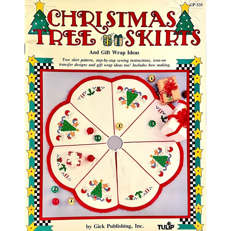 Op de afbeelding: Een witte kerstboomrok met rode bies en een rode strik. De rok is verdeeld in zes secties, elk met een ander geborduurd ontwerp van een kerstboom met ornamenten en cadeaus. De tekst "Christmas Tree Skirts" en "And Gift Wrap Ideas" staat gedrukt op de omslag van het boekje. De tekst "GP-535" staat gedrukt in de rechterbovenhoek van de omslag. De tekst "by Gick Publishing, Inc." staat gedrukt onderaan de omslag. De tekst "TULIP" staat gedrukt op een rood-wit lint in de rechterbenedenhoek van de omslag.