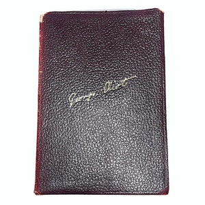 May include: A dark red leather-bound book with the name "George Eliot" written in gold lettering on the front cover.