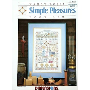 May include: A cross-stitch pattern booklet titled "Simple Pleasures Book Six" by Nancy Rossi. The cover features a framed cross-stitch design of a country scene with a quilt block pattern and the words "Simple Pleasures" in the center.