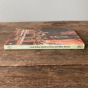 May include: A green paperback book with a picture of a group of people in a room. The book is titled "Lord Arthur Savile's Crime and Other Stories" by Oscar Wilde. The book's ISBN is 0 14 00.1021 1.