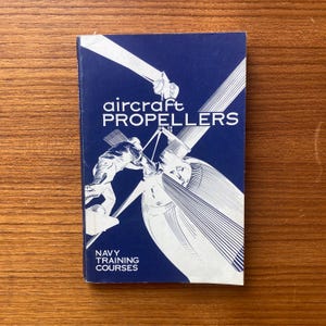 May include: A blue book with the title "aircraft PROPELLERS" and the text "NAVY TRAINING COURSES". The cover features a black and white illustration of a propeller.