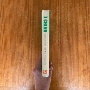 May include: A book spine with the title "I Ching" in green lettering. The text "Translated and edited by John Blofeld" is below the title. The spine is white with a green top and a logo at the bottom.