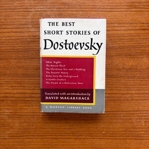 May include: A paperback book titled The Best Short Stories of Dostoevsky, translated by David Magarshack. The cover features a white top section, a central maroon rectangle with a list of stories, and a grey bottom section with Modern Library text.