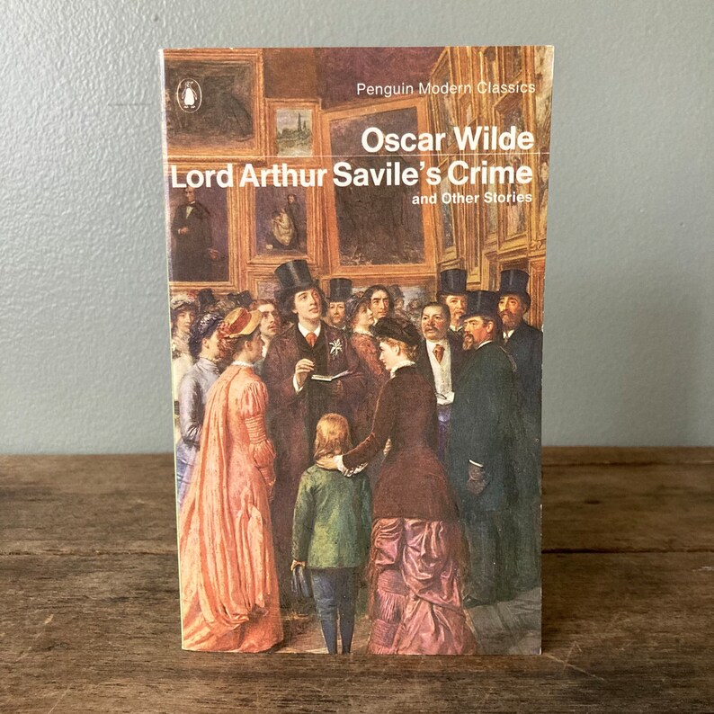 May include: A Penguin Modern Classics paperback book cover featuring an illustration of a group of people in a gallery setting. The book title is "Lord Arthur Savile's Crime and Other Stories" by Oscar Wilde.
