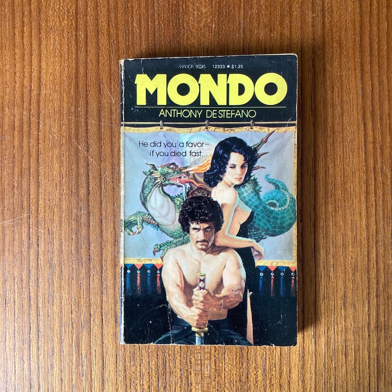 Puede incluir: Libro de bolsillo vintage titulado "MONDO" de Anthony De Stefano. La portada presenta a un hombre sin camisa sosteniendo una espada, una mujer y un drag&oacute;n. El libro tiene un t&iacute;tulo amarillo y negro con el texto "He did you a favor - if you died fast."