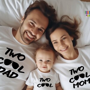 May include: Three white t-shirts with black text and sunglass graphics. The first shirt reads TWO COOL DAD, the second shirt reads TWO COOL, and the third shirt reads TWO COOL MOM. The shirts feature a crew neck and short sleeves in a matching set.
