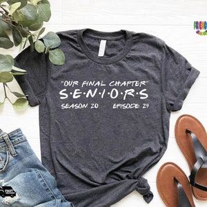 May include: A dark heather gray short-sleeve t-shirt featuring white text that reads "OUR FINAL CHAPTER" followed by "S E N I O R S" and "SEASON: 20 EPISODE: 24" printed in a bold, sans-serif font across the center of the chest area.