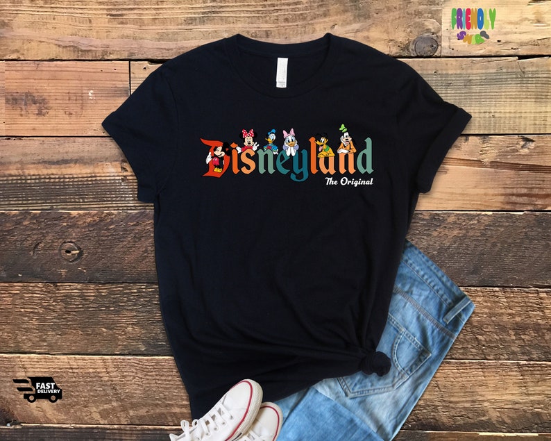 Puede incluir: Una camiseta negra con un gr&aacute;fico colorido de Mickey Mouse y sus amigos delante del texto "Disneyland The Original".