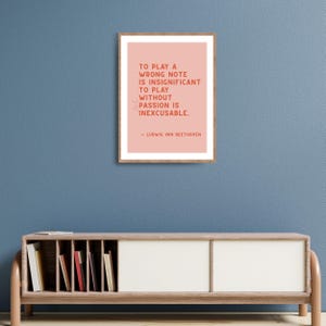 K&ouml;nnte beinhalten: Ein gerahmter Druck mit rosa Hintergrund und einem Zitat von Ludwig van Beethoven. Das Zitat lautet: "Einen falschen Ton zu spielen ist unbedeutend. Ohne Leidenschaft zu spielen ist unverzeihlich."