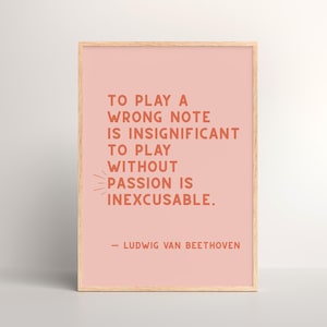 Op de afbeelding: Een roze ingelijste print met een citaat van Ludwig van Beethoven: "Een verkeerde noot spelen is onbeduidend. Spelen zonder passie is onvergeeflijk."