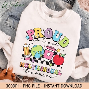 May include: A white crewneck sweatshirt featuring a colorful graphic with the text PROUD to teach MULTILINGUAL learners. The design includes a yellow pencil, a blue and green globe, a pink coffee cup, a red apple, and a black and white checkerboard.