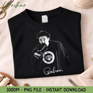 May include: Black sweatshirt featuring a grayscale image of a person wearing a hockey glove. The sweatshirt has a circular emblem with the words "WAR UNIVERSITY HAWKS" and the name "Graham" in cursive.