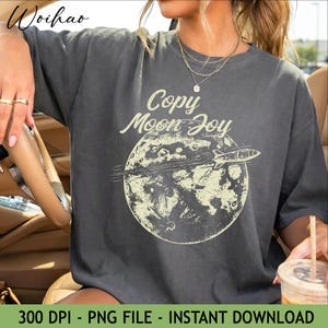Puede incluir: Camiseta gris oscuro con un gráfico color crema de una luna con un cohete y el texto "Copy Moon Joy". La camiseta también tiene el texto "300 DPI - PNG FILE - INSTANT DOWNLOAD" en la parte inferior.