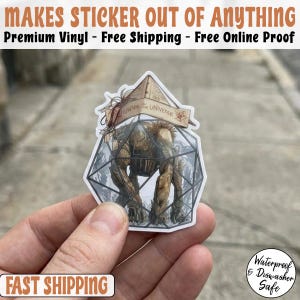 May include: A sticker featuring a detailed illustration of a creature inside a geometric glass enclosure. The sticker has the text "GAVIOS THE UNIVERSE" and is labeled "Waterproof & Dishwasher Safe". The sticker is held in a hand.