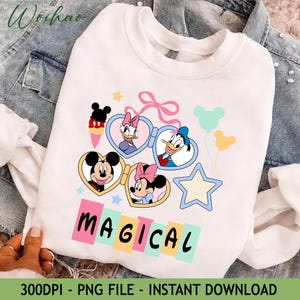 Op de afbeelding: Witte sweatshirt met een kleurrijke afbeelding van Mickey Mouse, Minnie Mouse, Donald Duck en Daisy Duck. Het ontwerp bevat hartvormige brillen, ballonnen en het woord "MAGICAL" in pastelkleuren. Een ster en een strik maken het ontwerp compleet.