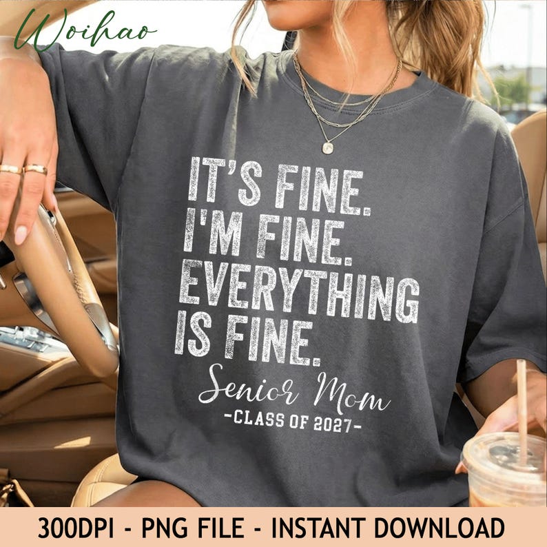 Op de afbeelding: Een antracietgrijs t-shirt met witte, verweerde tekst die luidt: IT'S FINE. I'M FINE. EVERYTHING IS FINE. SENIOR MOM CLASS OF 2027. Het t-shirt heeft een ronde hals en korte mouwen, met de afbeelding gedrukt in een vetgedrukt lettertype.