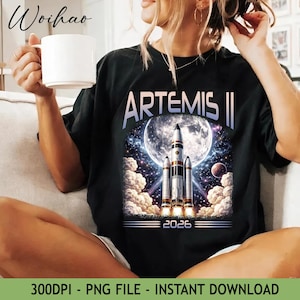 Puede incluir: Camiseta negra con un diseño espacial. Muestra un cohete lanzándose hacia una luna llena, con las palabras "ARTEMIS II" y el año "2026". El diseño incluye nubes, estrellas y planetas.