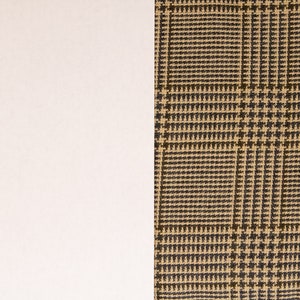 Puede incluir: Primer plano de una tela de cuadros marrones y beige con fondo blanco.