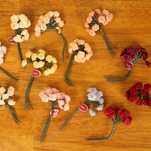 May include: Assortment of 10 small artificial flower bunches in various colors, including pink, yellow, red, and white. Each bunch is made of fabric and has a wire stem.