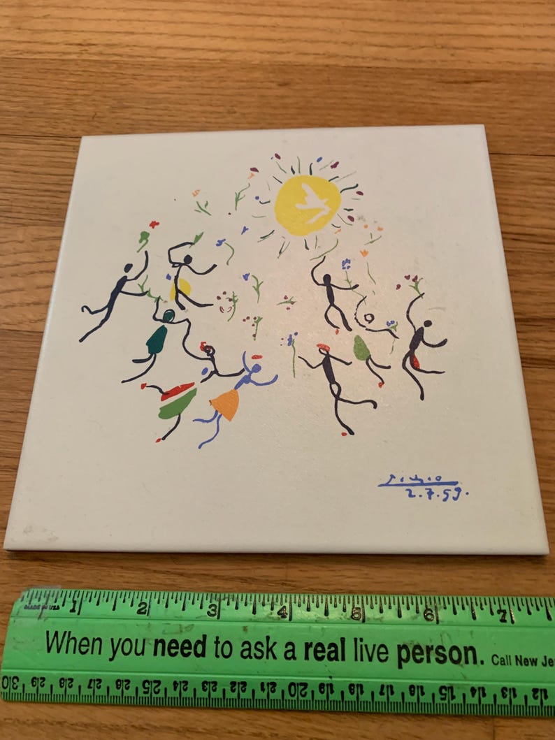 Pu&ograve; includere: Una piastrella di ceramica bianca con un'illustrazione colorata disegnata a mano di persone che ballano intorno a un sole giallo. La piastrella &egrave; firmata "2.7.59."