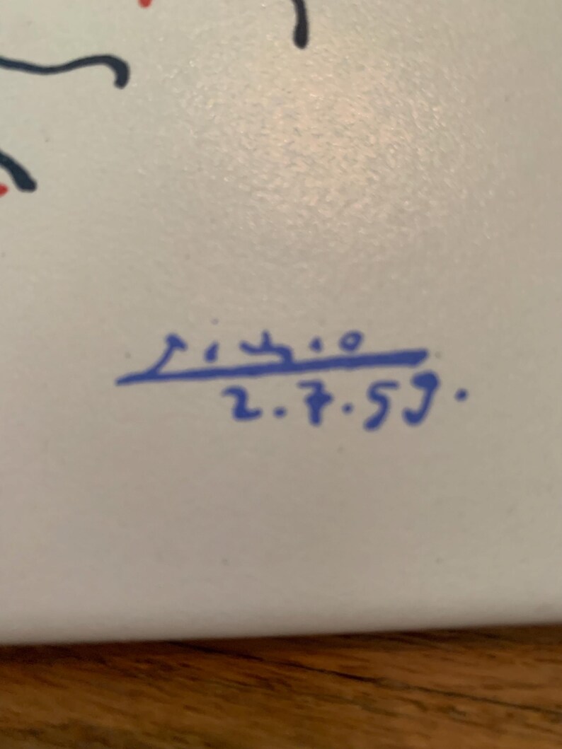 Pu&ograve; includere: Una piastrella di ceramica bianca con un design astratto blu e nero. La piastrella &egrave; firmata "Picasso 2.7.59."