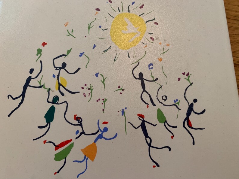 Pu&ograve; includere: Uno sfondo bianco con un sole giallo con un uccello bianco al suo interno.  Ci sono figure di bastoncini di vari colori che ballano intorno al sole.  Le figure di bastoncini tengono fiori e ci sono fiori sparsi intorno al sole.