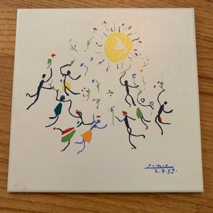 Pu&ograve; includere: Una piastrella di ceramica bianca con un dipinto colorato di figure stilizzate che ballano intorno a un sole giallo. La piastrella &egrave; firmata "Mir&oacute; 2.7.59."
