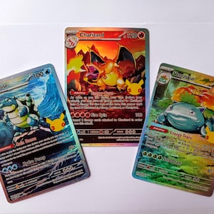 May include: Three Pokémon trading cards featuring Blastoise, Charizard, and Venusaur. Each card displays colorful character illustrations, text, and symbols. The Blastoise card is blue, the Charizard card is red and orange, and the Venusaur card is green.