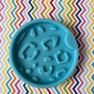 May include: A light blue silicone mold with a leopard print design. The mold is round and has a smooth surface.
