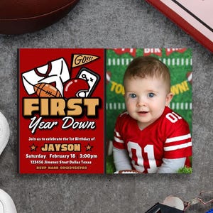 Könnte beinhalten: Rote und goldene Einladung zum ersten Geburtstag mit Football-Motiv. Die Einladung zeigt einen Football, einen Helm und den Text "FIRST Year Down". Auf der rechten Seite befindet sich ein Foto eines Babys in einem Football-Trikot.