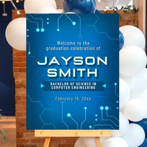 May include: A blue graduation celebration sign on a wooden easel, with white and blue balloons in the background. The sign reads "Welcome to the graduation celebration of JAYSON SMITH, Bachelor of Science in Computer Engineering, February 18, 20xx."