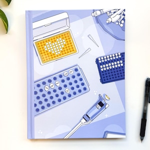 May include: A blue notebook with a colorful illustration of laboratory equipment, including a pipette, a 96-well plate, and a microplate. The illustration is on a light blue background with white stars.