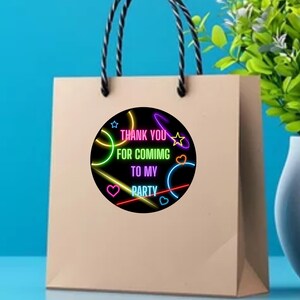 Puede incluir: Una bolsa de regalo de papel marr&oacute;n con una pegatina redonda que dice "Gracias por venir a mi fiesta". La pegatina tiene un dise&ntilde;o de ne&oacute;n con c&iacute;rculos y estrellas de colores.