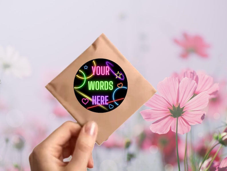 Puede incluir: Un sobre de papel marr&oacute;n con una pegatina redonda con luces de ne&oacute;n rosa, azul, verde y amarillo. La pegatina dice "YOUR WORDS HERE" en texto negro.